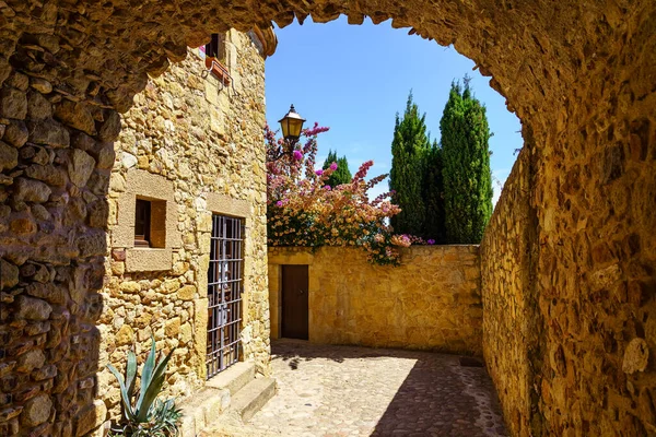 Stone arch in an alley with stone houses in the medieval town of Pals, Girona