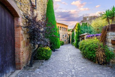 Peratallada, Girona, Katalonya köyünde günbatımında çiçek ve bitkilerle dolu eski taş evler.