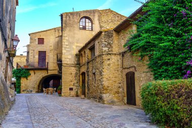 Bir yaz günü gün batımında yeşil sarmaşıklı ortaçağ taş evleri, Peratallada, Girona, Katalonya
