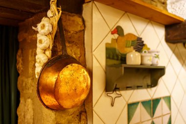 Klasik mutfak gereçleri, tavalar ve sarımsak duvardan sarkan eski usul.