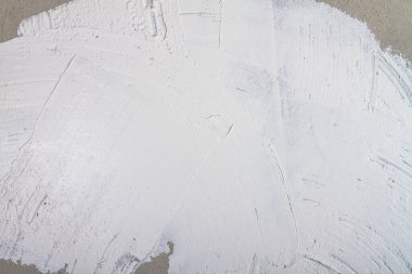 Arka plan beyaz macunla sıvanmış düzensizlikler, lekeler ve alçıda çizikler olan bir duvardan yapılmış..