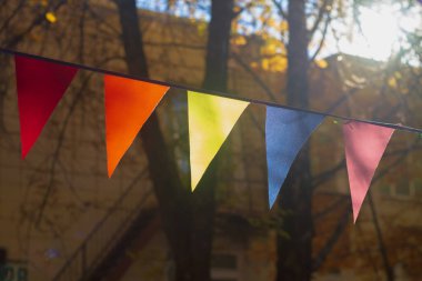 Sonbaharda sonbahar ağaçlarının arasında asılı renkli bayraklar.