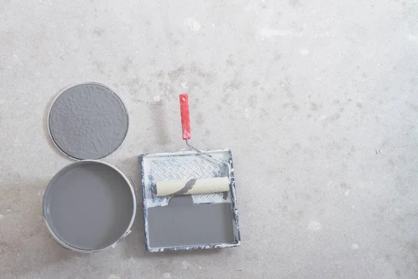 Vernice grigia in un barattolo, un vassoio con vernice e un rullo per lavori di pittura, preparazione per dipingere il muro durante la ristrutturazione dell'appartamento — Foto Stock