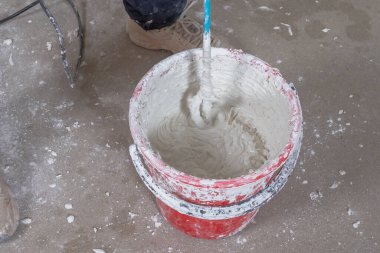 Macun karışımını duvar macunu için bir kovada karıştırıcı ile karıştır