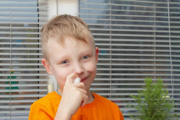 一个在鼻子里喷药的男孩的画像 这个男孩治疗鼻涕和流鼻涕 — 图库照片