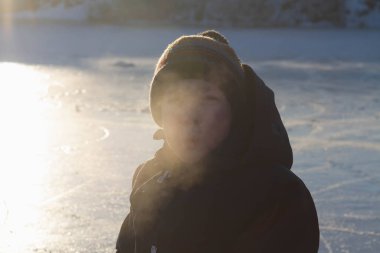 Doğada kışın çocuğun nefesinden buhar çıkıyor..