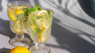 Limonlu mojito. Nane yapraklı. Gri arka planda, açık gölgeli..