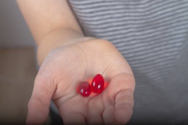 İlacın iki şeffaf kırmızı kapsülü bir insanın avucunda..