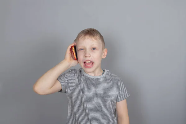 Ένα Ξανθό Καυκάσιο Αγόρι Μιλάει Ένα Κόκκινο Smartphone Και Χαμογελά — Φωτογραφία Αρχείου