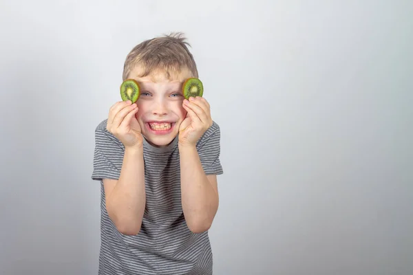 Wesoły Biały Chłopiec Zamknął Oczy Plastrami Zielonych Owoców Kiwi Szarym — Zdjęcie stockowe