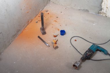 Duvarları yıkmak için elektrik yumruğu, balyoz, levye, beton zeminde tuğla parçaları.