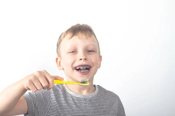 Kaukasische jongen poetst zijn tanden met zwarte tandpasta met houtskool — Stockfoto