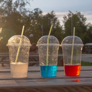 Plastik bardaklarda karbonatlı su ve bir yaz günü bir sokak kafesinde kokteyl tüpleri..