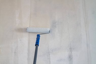 Boyanmadan ya da duvar kağıdı yapıştırmadan önce astar macun duvarlı bir silindirle asılmış..