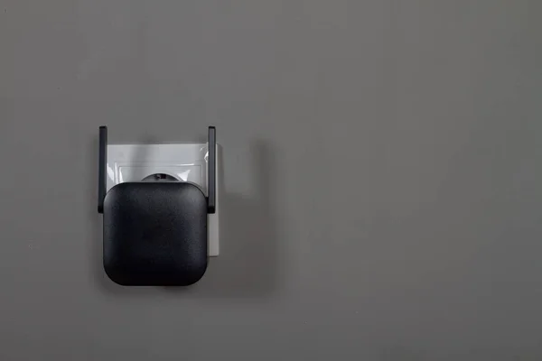 Siyah Bir Sinyal Yükselticisi Gri Duvar Arkaplanındaki Bir Prize Takılmış — Stok fotoğraf