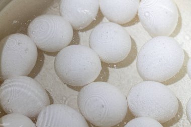 Tavuk yumurtaları beyaz tencerede sıcak suda kaynatılır..