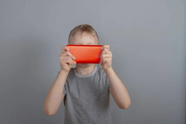 Niño Está Jugando Juego Teléfono Inteligente Rojo Cubierto Cara Ojos —  Fotos de Stock