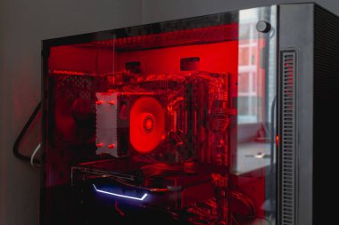 Bilgisayar sistemi ünitesinin iç parçaları: daha havalı, sabit disk, anakart, kırmızı arka planda video kartı.