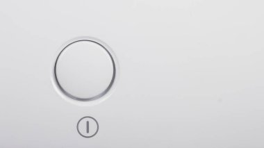 The start button, the on and off button of the device on the white surface.