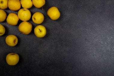 Elmalar siyah arka planda altın değerindedir. Parlak sarı elmalar siyah taş masaya saçılmış..