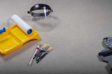 Duvarları ya da tavanları boyamak için kullanılan bir alet, fırçalar, silindirler, tepsiler, beton zeminde eldivenler. arkaplan.