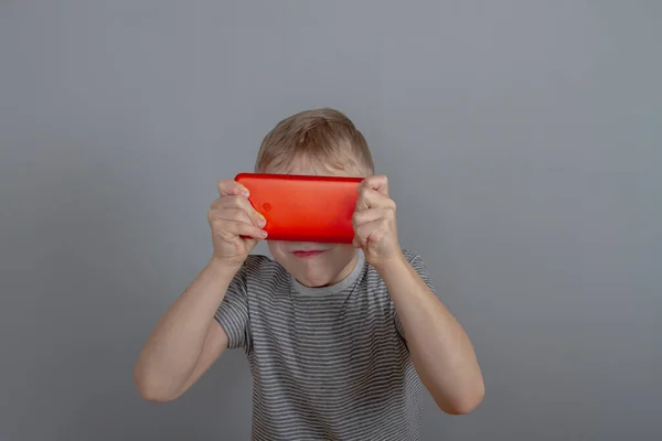 Der Junge Spielt Ein Spiel Auf Einem Roten Smartphone Und — Stockfoto
