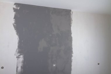 Evde gri boyalı bir duvar var, boya beyaz bir duvarda kuruyor..