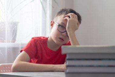 Gözlüklü genç bir beyaz okul çocuğu derslerden, okuldan, ödevlerden ve elleriyle başını tutmaktan bıktı..