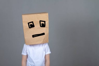 Kafasında beyaz bir tişört ve kare gözlü bir çocuk. Üzgün yüz ifadesi, bilgisayar oyunlarının yorgunluğu, gri arka plan..