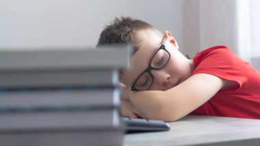 Gözlüklü beyaz bir öğrenci derslerden, okuldan, ödevlerden bıktı ve masasında uyudu..