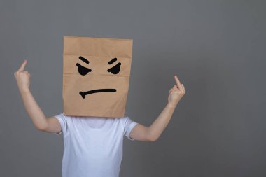 Kafasında kese kağıdı olan kızgın bir çocuk, kızgın duyguları olan tanınmayan bir adam orta parmak hareketi gösteriyor..