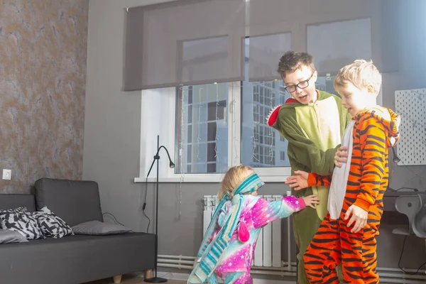 Dzieci bracia i siostry w piżamie kigurumi grają ślepca w domu — Zdjęcie stockowe