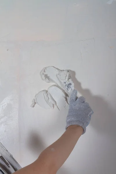 Masilla de la pared en la casa con masilla usando una espátula para nivelar las irregularidades de la superficie —  Fotos de Stock