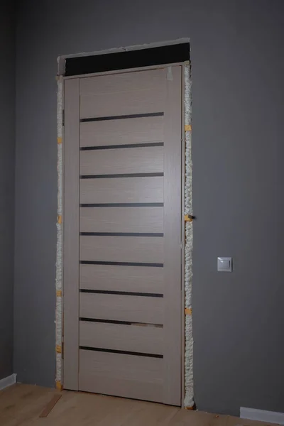 Τοποθέτηση της πόρτας στο δωμάτιο στην πόρτα, στερέωση της πόρτας με αφρό στερέωσης — Φωτογραφία Αρχείου