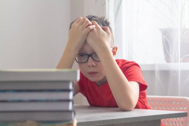 Gözlüklü genç bir beyaz okul çocuğu derslerden, okuldan, ödevlerden ve elleriyle başını tutmaktan bıktı..