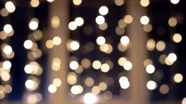 Bulanık koyu bir arkaplan ve Noel tatili için camda parlayan çelenk var..