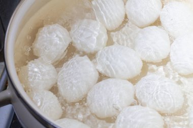 Tavuk yumurtaları beyaz tencerede sıcak suda kaynatılır..