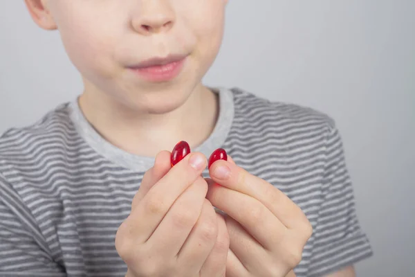Biały Chłopiec Trzyma Rękach Dwie Czerwone Pigułki Leku — Zdjęcie stockowe