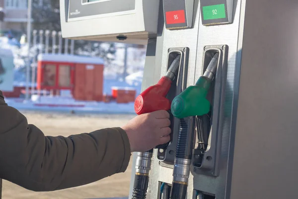 To fill up the car with gasoline at the gas station, a man pours gasoline into the tank of a white car in winter.