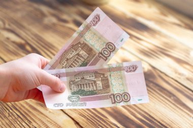 Bir insanın elinde yüz Rus rublesi var..