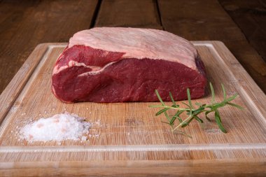 Bir parça sığır filetosu, biberiye ve bambu kesme tahtasında tuz.