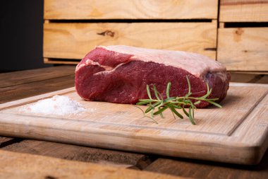 Bir parça sığır filetosu, biberiye ve bambu kesme tahtasında tuz.