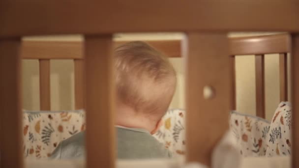 Bebelușul stă în pătuț și se târăște printre perne în apropiere — Videoclip de stoc
