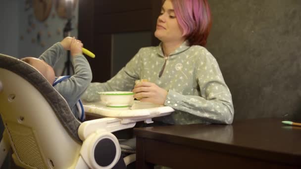 Ibu mencoba untuk memberi makan anaknya dengan puree dari guci tapi dia merampok sendok dan gelombang di udara — Stok Video