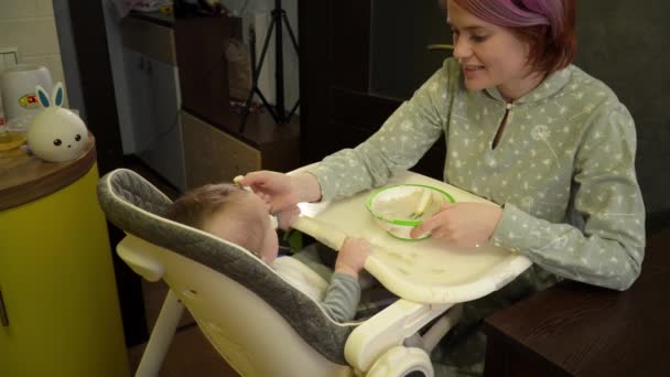 Junge kaukasische Mutter füttert ihr Baby mit Haferbrei und er will kein Kopfschütteln essen — Stockvideo