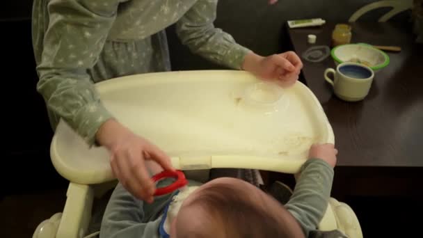Joven mujer caucásica está limpiando los primeros dientes a su pequeño hijo después de la comida filmada desde arriba — Vídeos de Stock