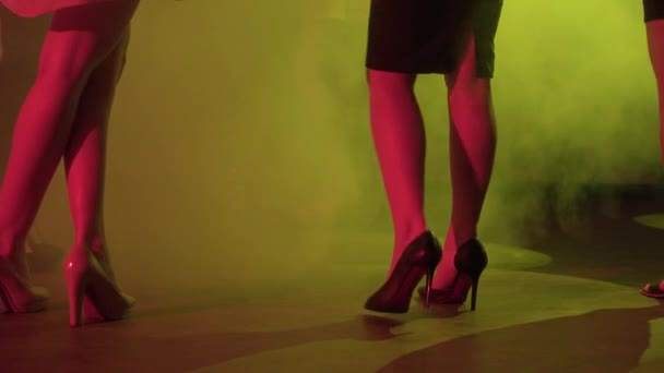 Молоді леді на високих підборах танцюють в нічному клубі серед диму і легкого шоу — стокове відео