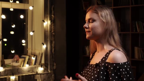 Wanita muda Kaukasia diwawancarai tinggal di kamar dengan karangan bunga dan rak buku di latar belakang — Stok Video