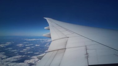 Kanatlarındaki ve yeryüzündeki uçak penceresinden bulutlu manzarayı izle