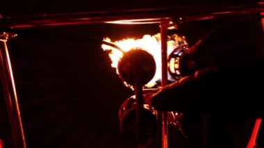 Sıcak hava balonunda gaz teçhizatından çıkan parlak alevler ve pilotluk yapan bir adam.